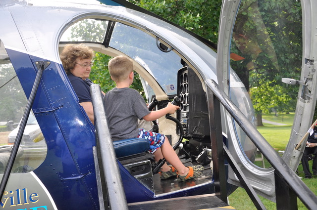 Boy and woman inside Louisville Police helicopter cockpit, boy holding controls.